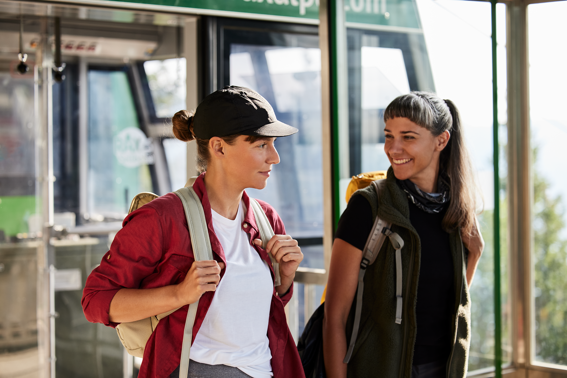 Zwei Wanderinnen stehen fröhlich am Ausgangspunkt ihrer Tour, umgeben von der majestätischen Kulisse der Wiener Alpen. Die frische Bergluft und die Vorfreude auf das Abenteuer in der Natur schaffen eine einladende Atmosphäre für alle, die die Schönheit der Berge erleben möchten.