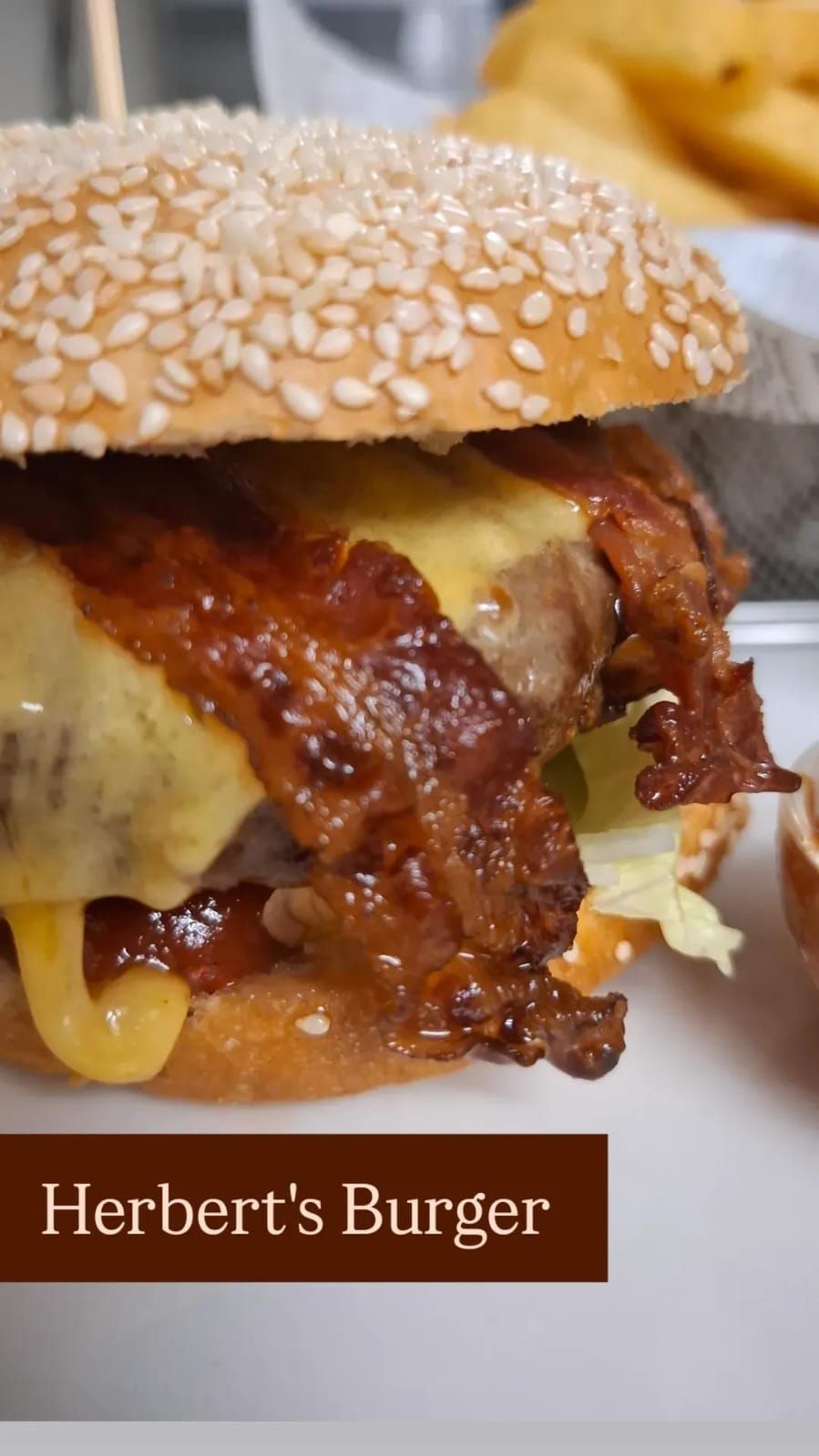 Nahaufnahme eines Burgers mit Sesambrötchen, geschmolzenem Käse und knusprigem Speck.