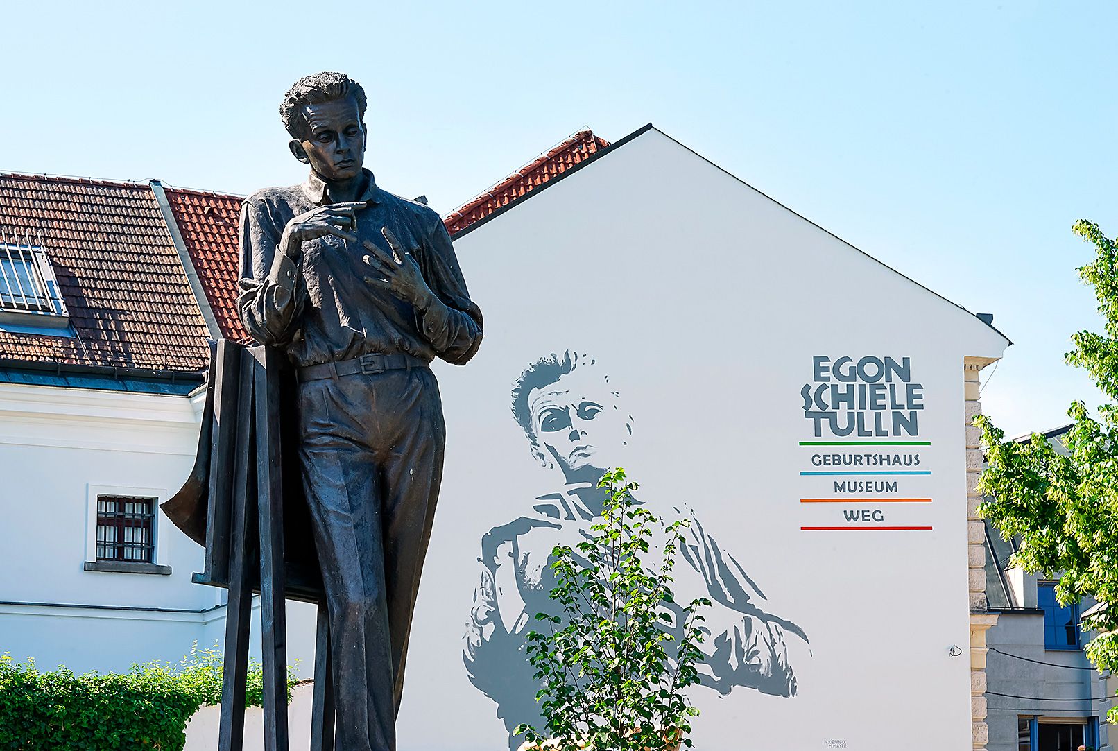 Statue vor dem Egon Schiele Museum in Tulln mit Wandbild im Hintergrund.