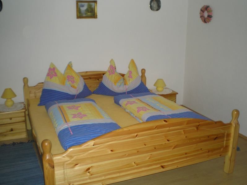 Holzbett mit bunter Bettwäsche in einem Schlafzimmer.