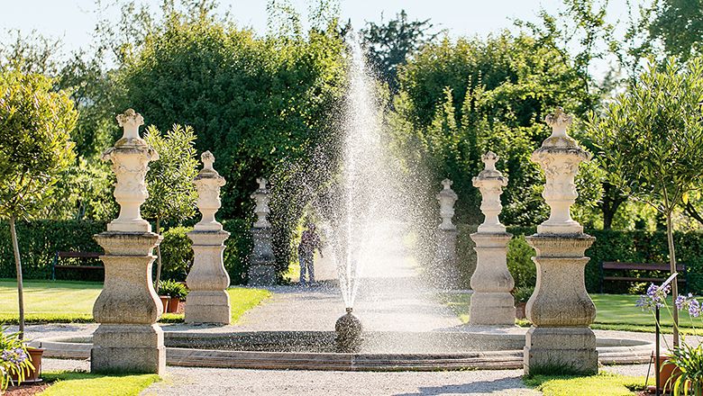Springbrunnen im Garten des Stifts Seitenstetten mit Statuen und Bäumen im Hintergrund.