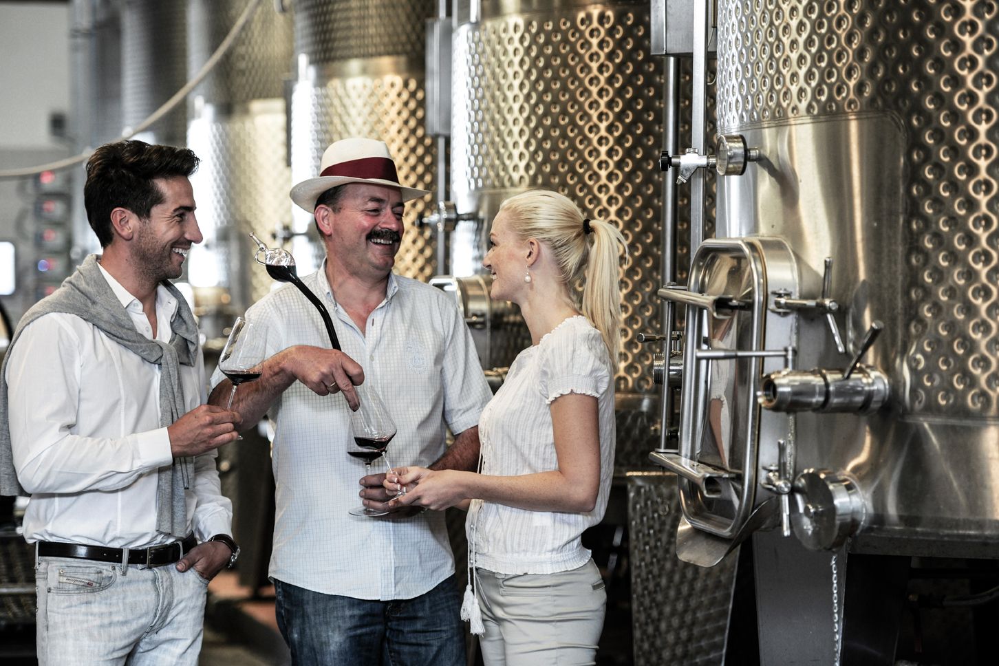 Drei Personen bei einer Weinverkostung in einem Weingut.