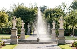 Der historische Hofgarten verzaubert mit seiner harmonischen Anordnung von kunstvoll gestalteten Brunnen und eleganten Statuen. Umgeben von üppigem Grün und blühenden Pflanzen lädt dieser Ort zum Verweilen und Träumen ein, während das sanfte Plätschern des Wassers eine beruhigende Atmosphäre schafft.