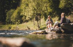 Zwei Radfahrerinnen genießen eine kurze Pause am Wasser.