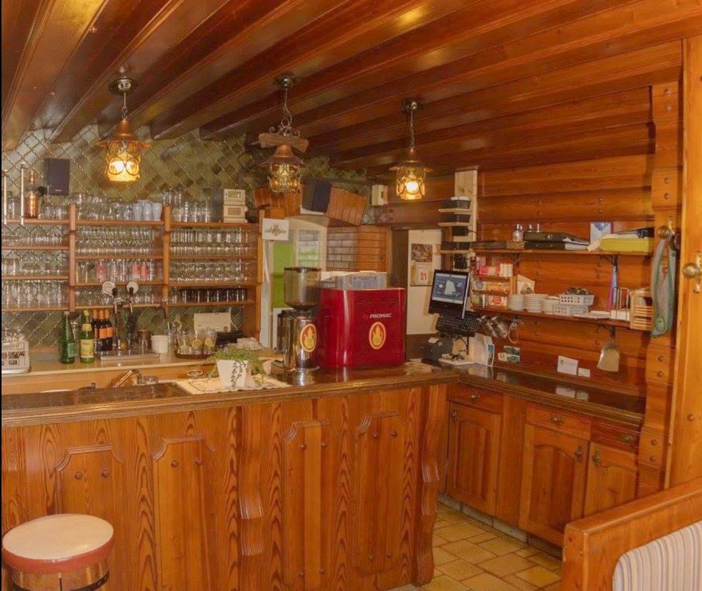 Rustikaler Schankbereich mit Holzmöbeln und Gläsern.