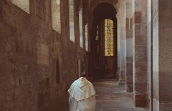 Ein stiller Moment in den ehrwürdigen Hallen des Stifts Heiligenkreuz, wo die sanften Lichtstrahlen durch die bunten Fenster tanzen. Die Atmosphäre ist geprägt von einer tiefen Spiritualität und der Ruhe, die nur an solchen heiligen Orten zu finden ist.