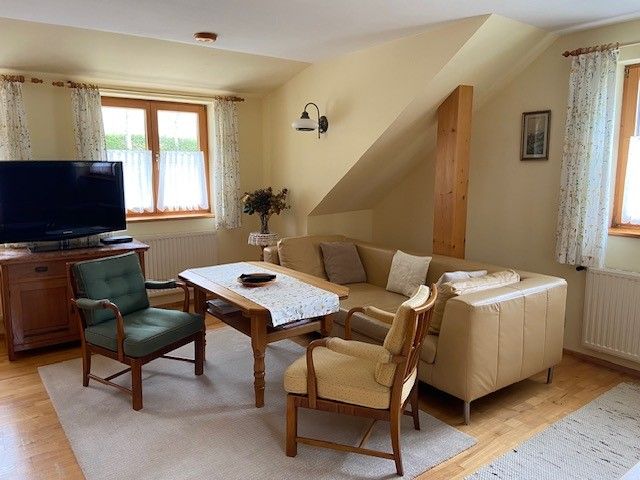 Gemütliches Wohnzimmer mit Sofa, Sesseln und Fernseher.