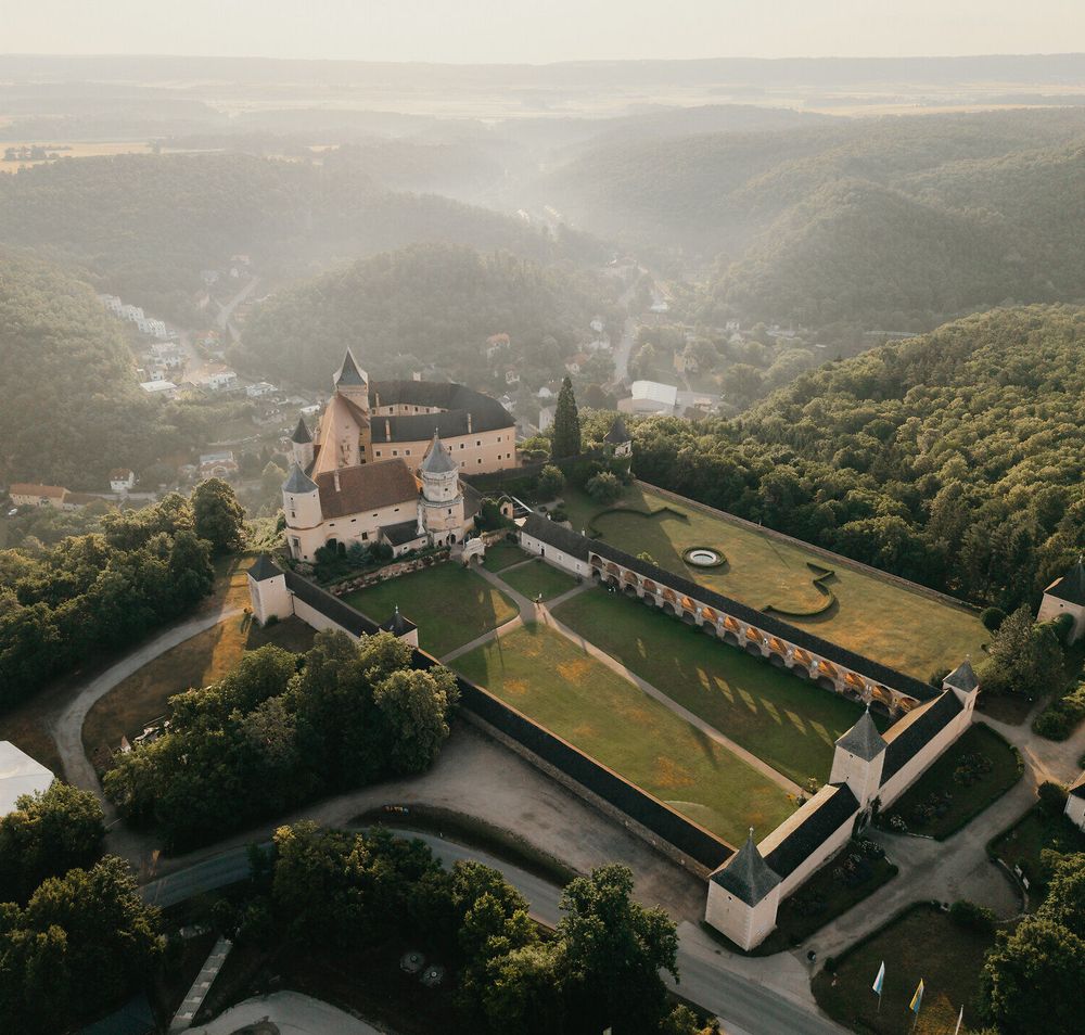 Luftaufnahme von Schloss Rosenburg inmitten bewaldeter Hügel im Waldviertel.