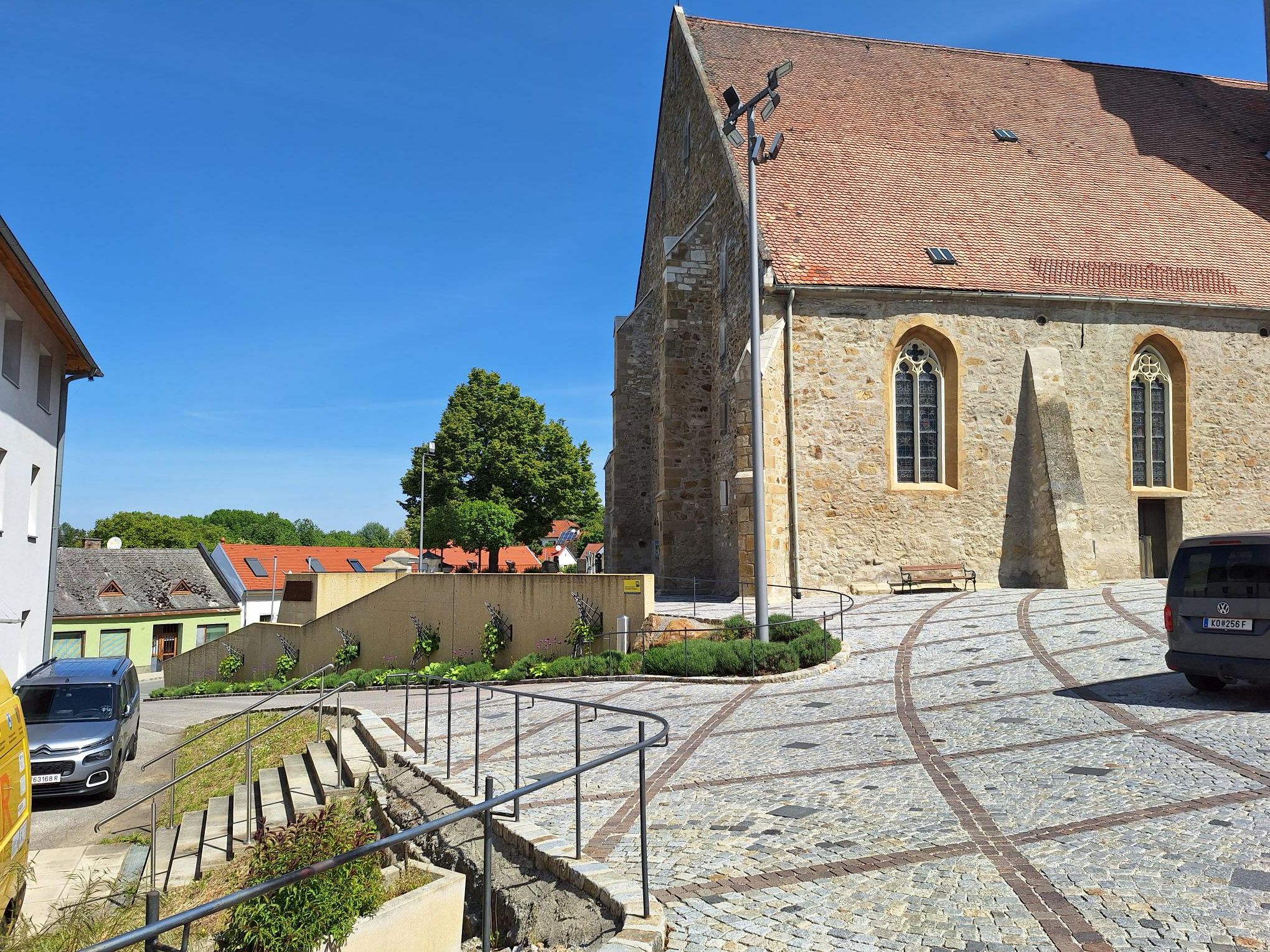 Steintreppe führt zu einem historischen Gebäude mit roten Ziegeldach und gotischen Fenstern.