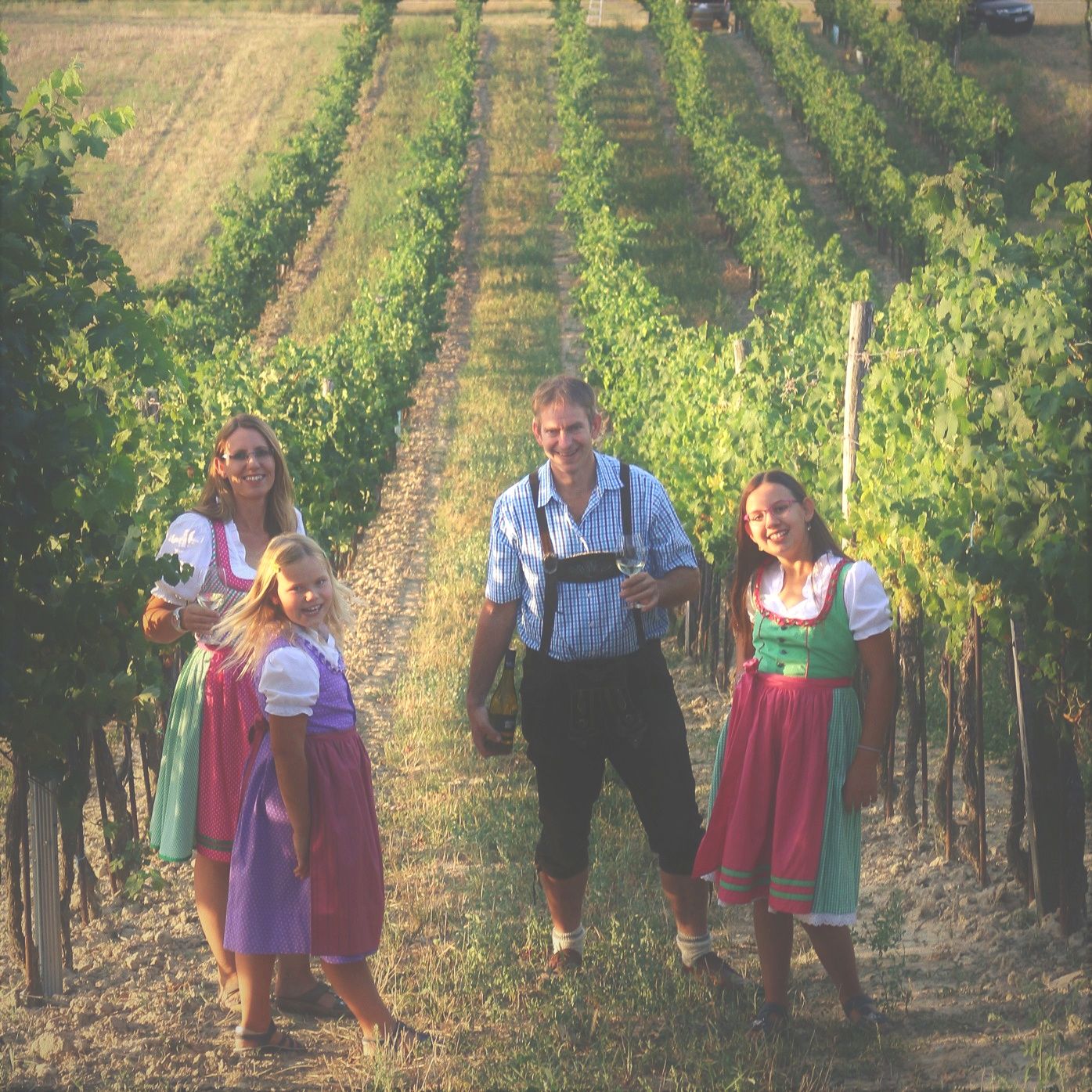 Familie in traditioneller Kleidung in einem Weinberg.