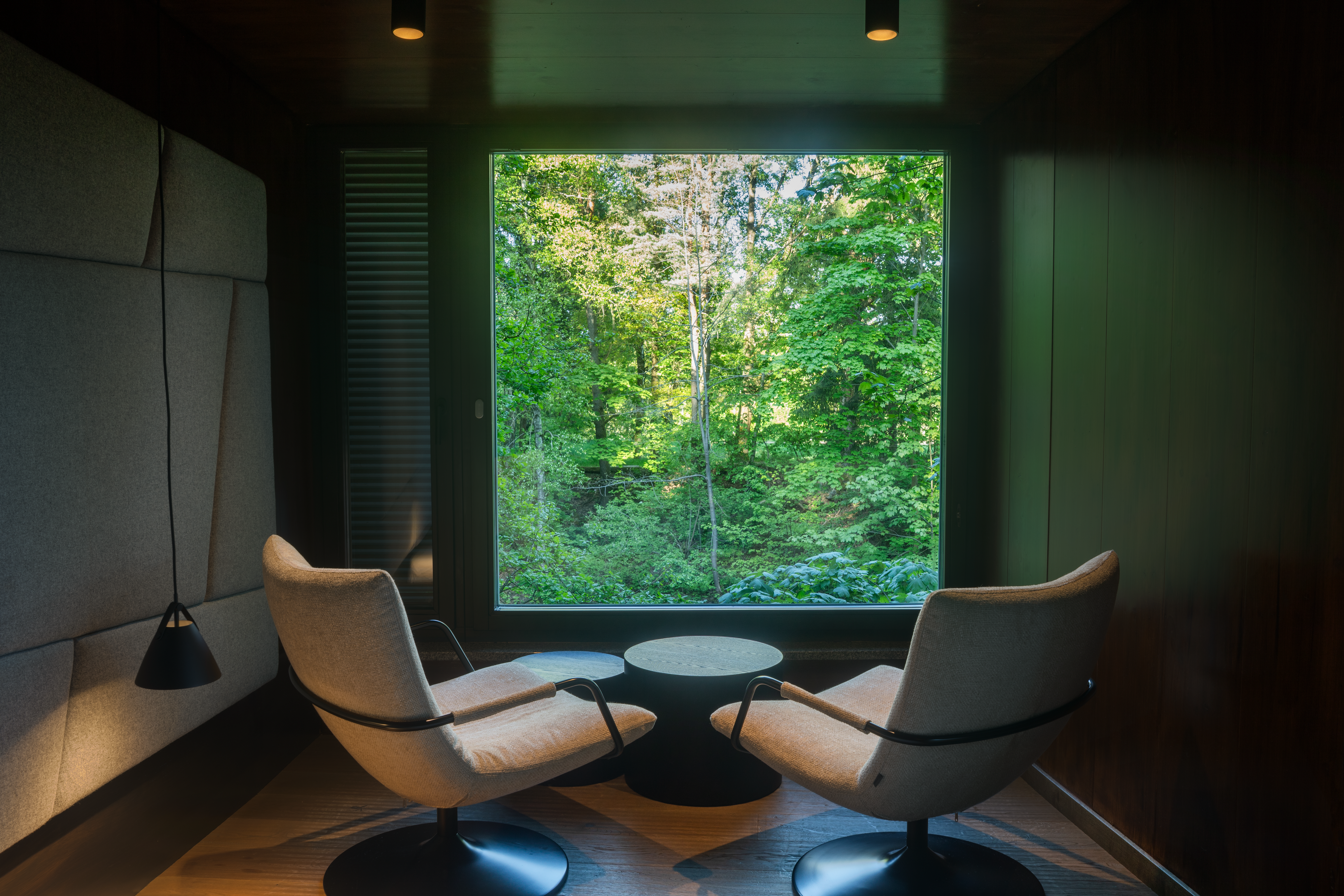 Modernes Baumhaus im Wald mit Balkon und Glasfront.