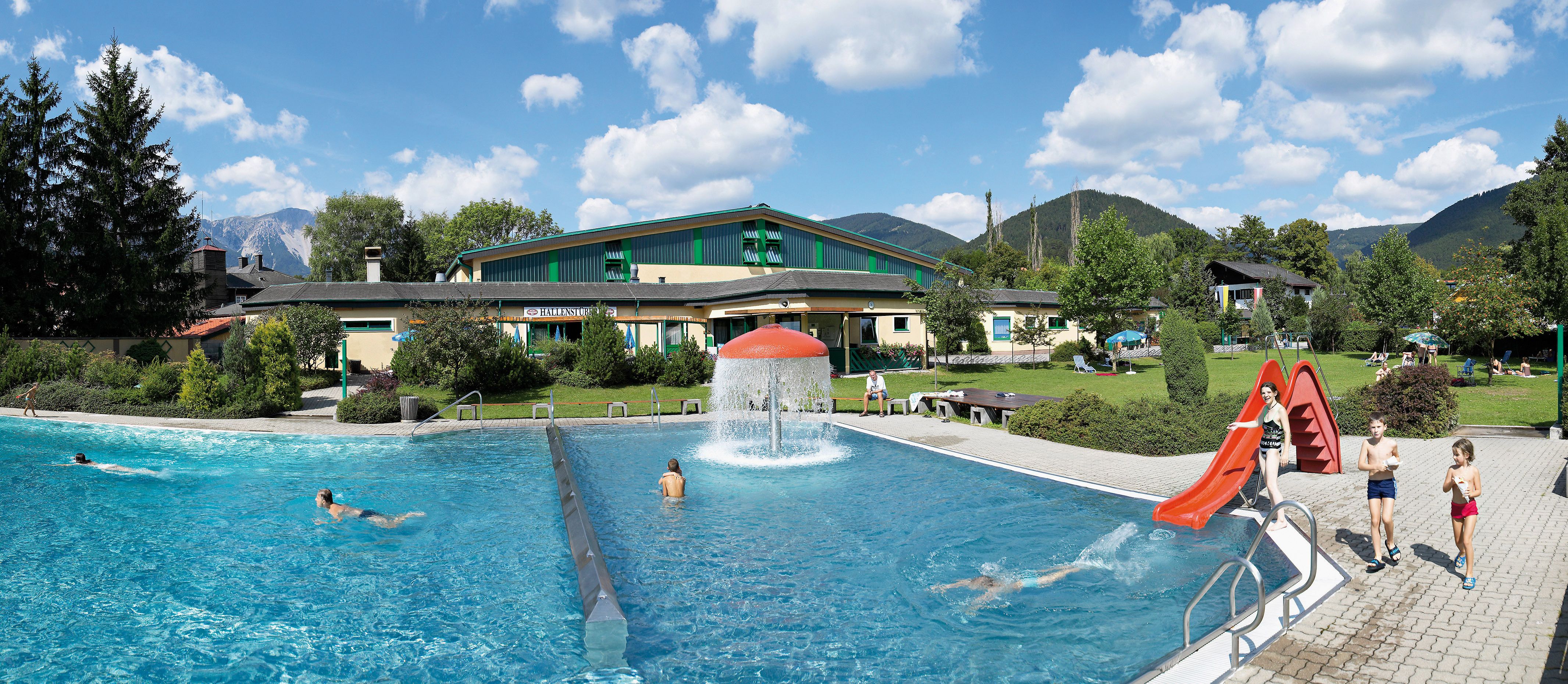 Freibad Puchberg mit Schwimmbecken, Rutsche und grüner Umgebung.