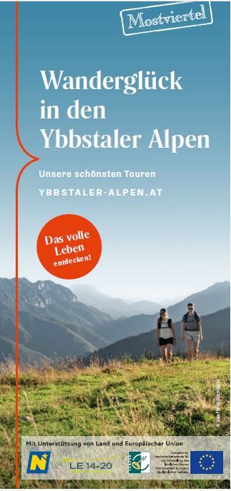 Coverbild: 2 Personen wandern durch eine Wiese, dahinter sieht man das Bergpanorama der Ybbstaler Alpen. 