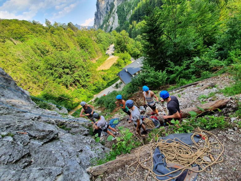 Gruppe von Kletterern mit Helmen an einem Felsen im Wald.