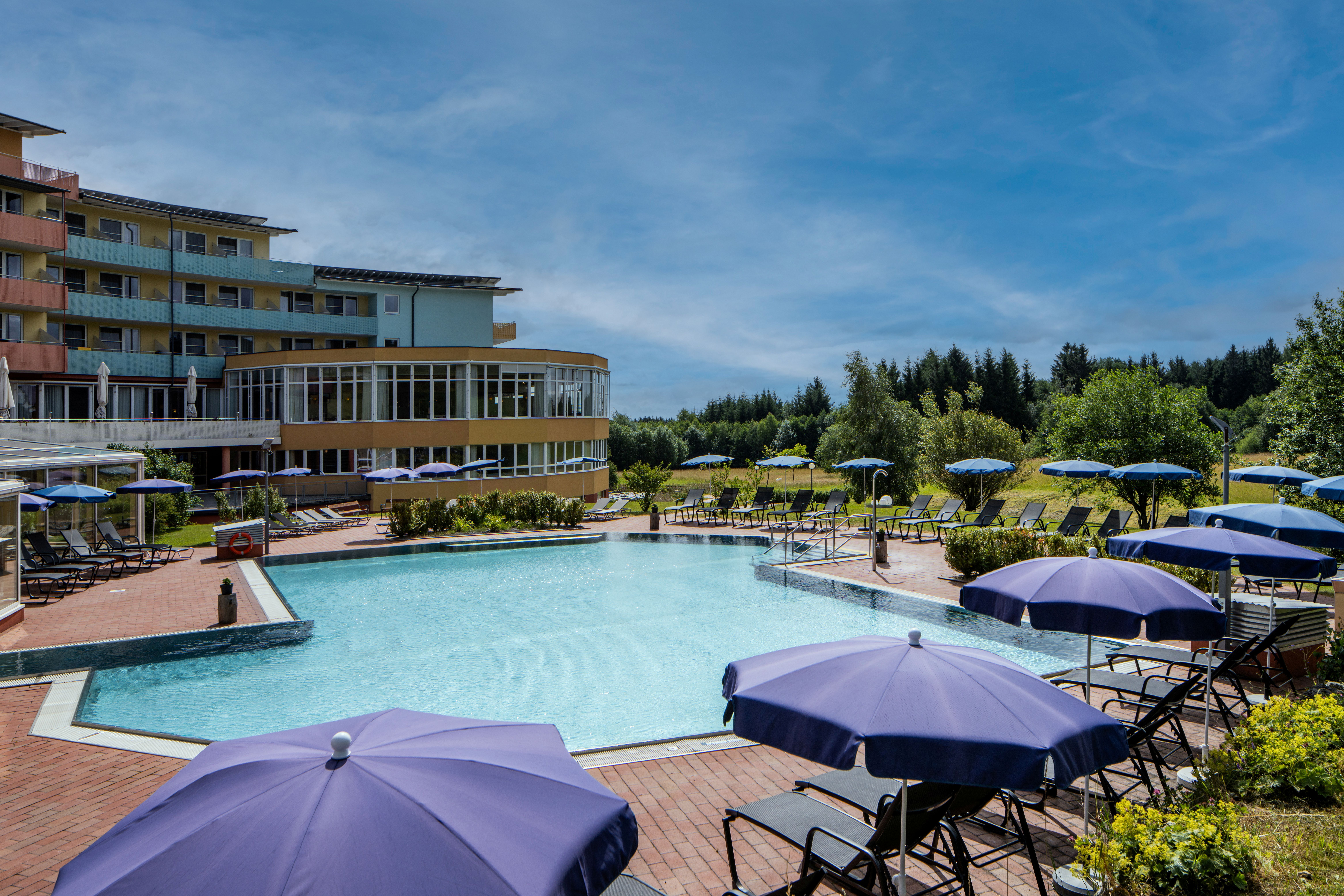 Außenansicht eines Hotels mit Pool und Sonnenschirmen.