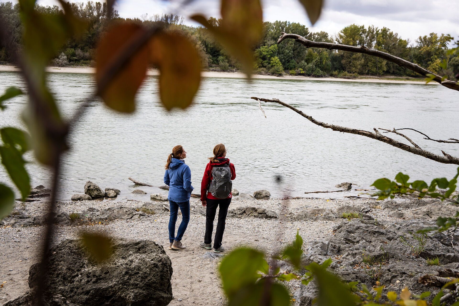 Zwei Frauen stehen am Donauufer und blicken aufs Wasser. 
