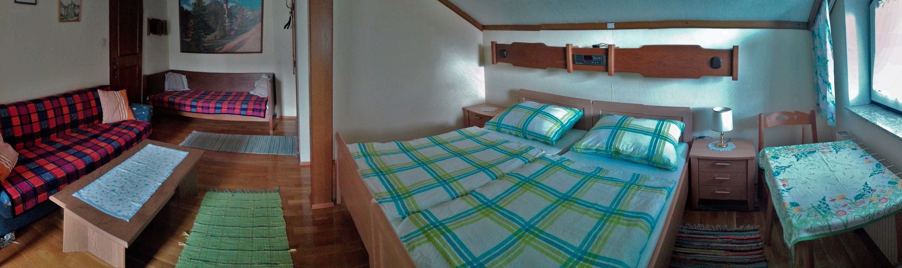 Ein gemütliches Zimmer mit Doppelbett, Sofa, Tisch und Fenster.