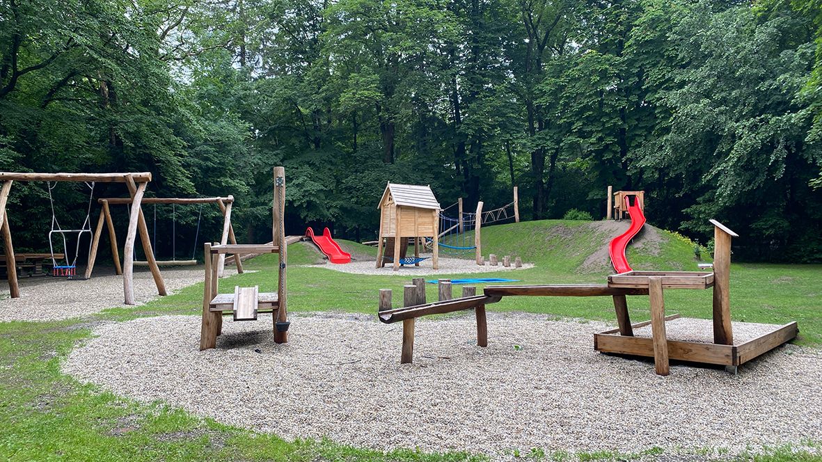 Spielplatz im Stadtpark mit Schaukeln, Rutsche und Klettergerüst.