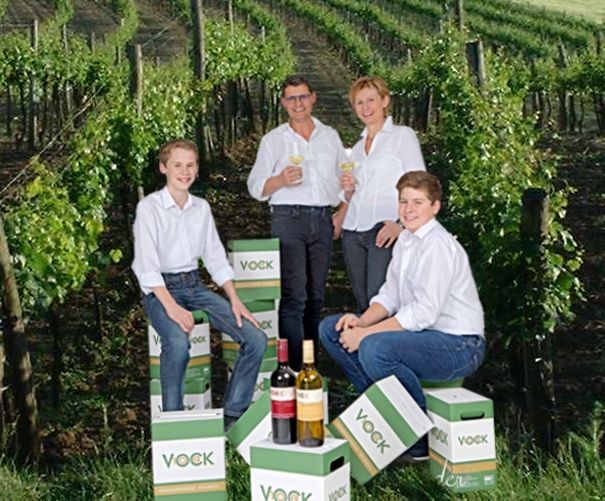 Vier Personen in einem Weinberg mit Vock-Weinkartons.