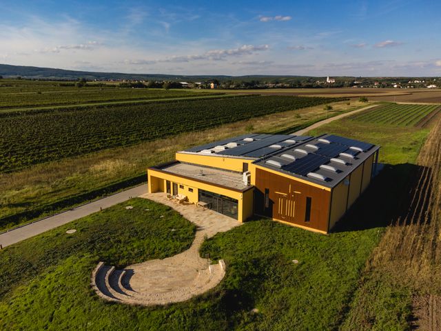Luftaufnahme eines modernen Weinguts mit Solarpanelen, umgeben von Weinbergen und Feldern.