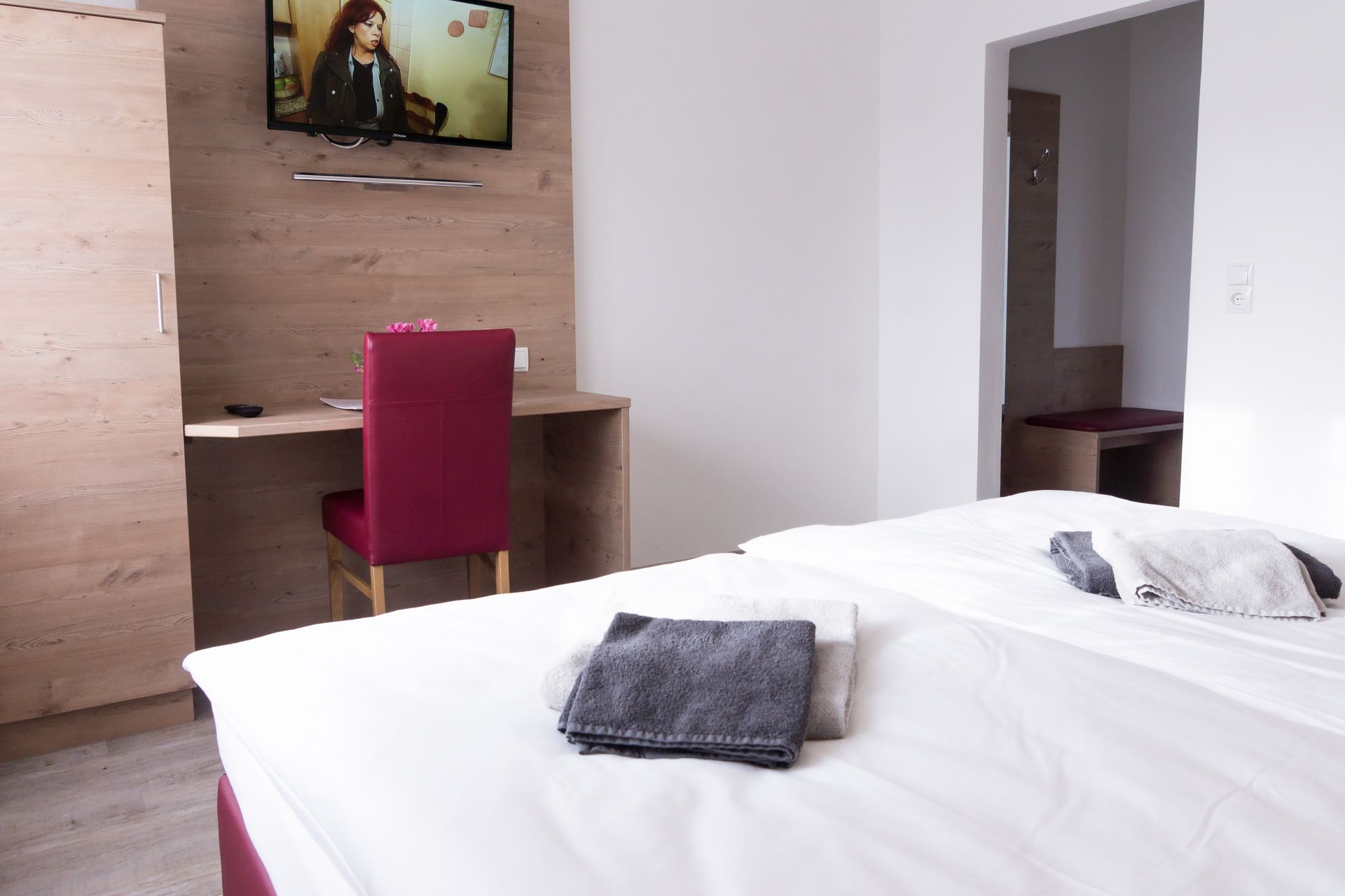 Doppelzimmer mit Bett, Schreibtisch, Stuhl und Fernseher an der Wand.