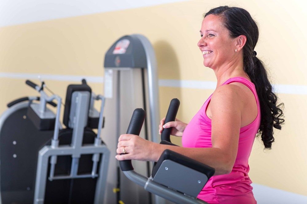 Frau trainiert auf einem Crosstrainer im Fitnessstudio.