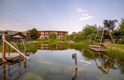 Naturhotel Molzbachhof mit Teich und Liegestühlen im Vordergrund.