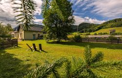 Ein goldener Zug hält am Bahnhof Wienerbruck-Josefsberg, umgeben von grüner Landschaft und einem kleinen Sitzbereich im Freien.
