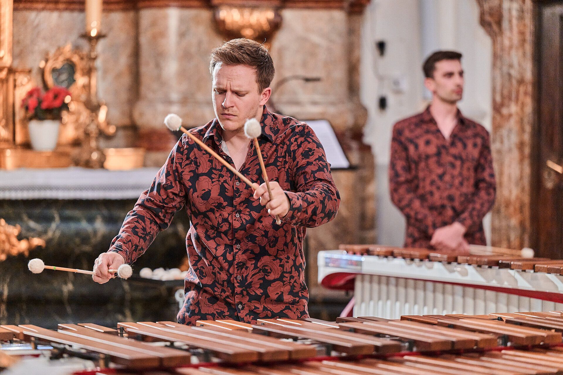 Musiker spielt Marimbafon in barocker Kirche beim Barockfestival St. Pölten, im Hintergrund weiterer Percussionist vor historischem Altarraum.