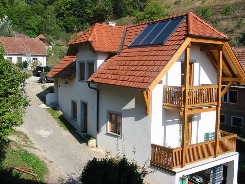 Ferienwohnung mit rotem Dach und Solarpanelen in ländlicher Umgebung.