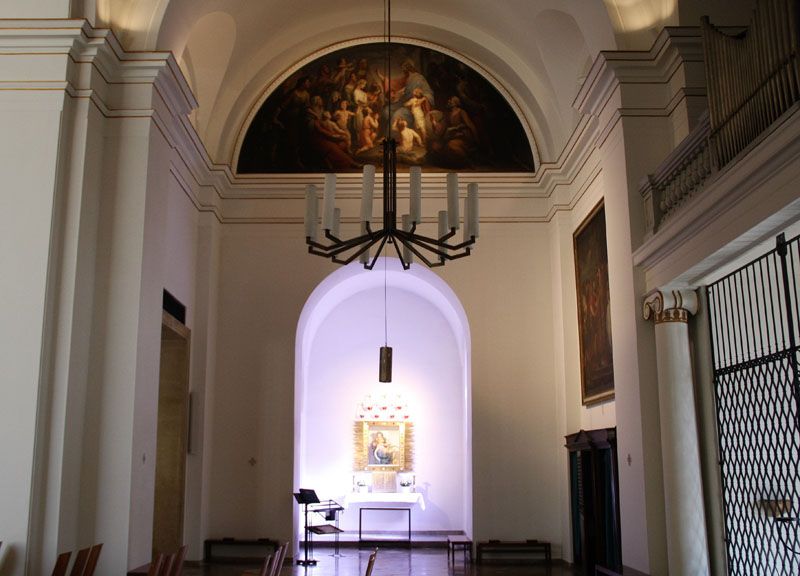 Innenansicht einer Kirche mit Altar und Gemälde an der Wand.