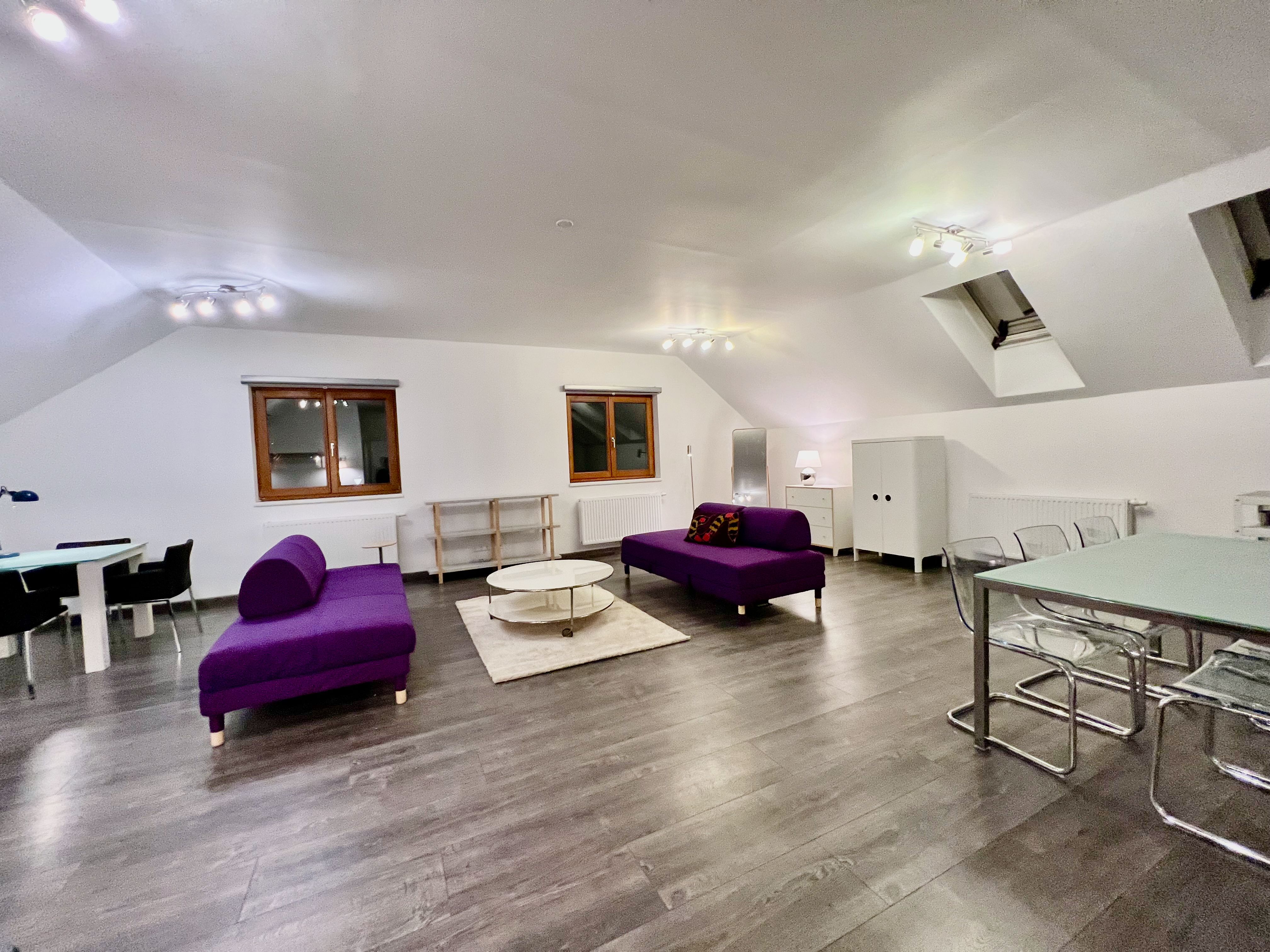 Modernes Loft mit violetten Sofas, Esstisch und Holzboden.