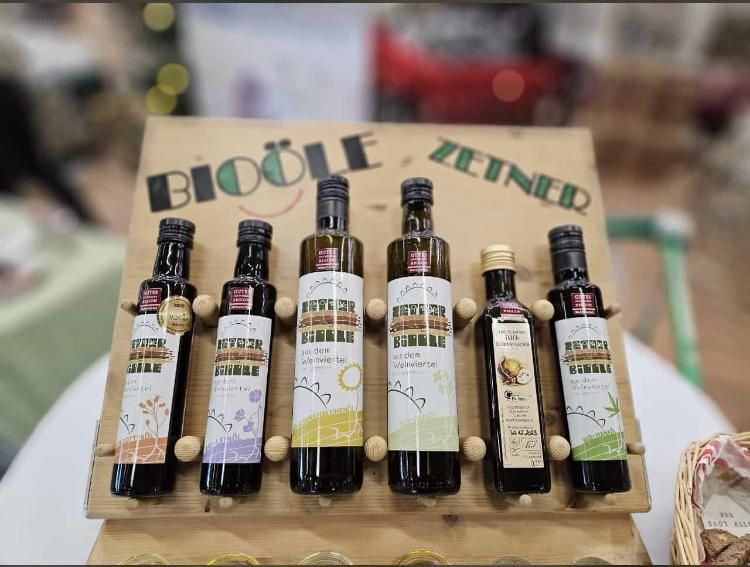 Fünf Flaschen Bio-Öl auf einem Holzständer mit der Aufschrift 'Bioöle Zeiner'.