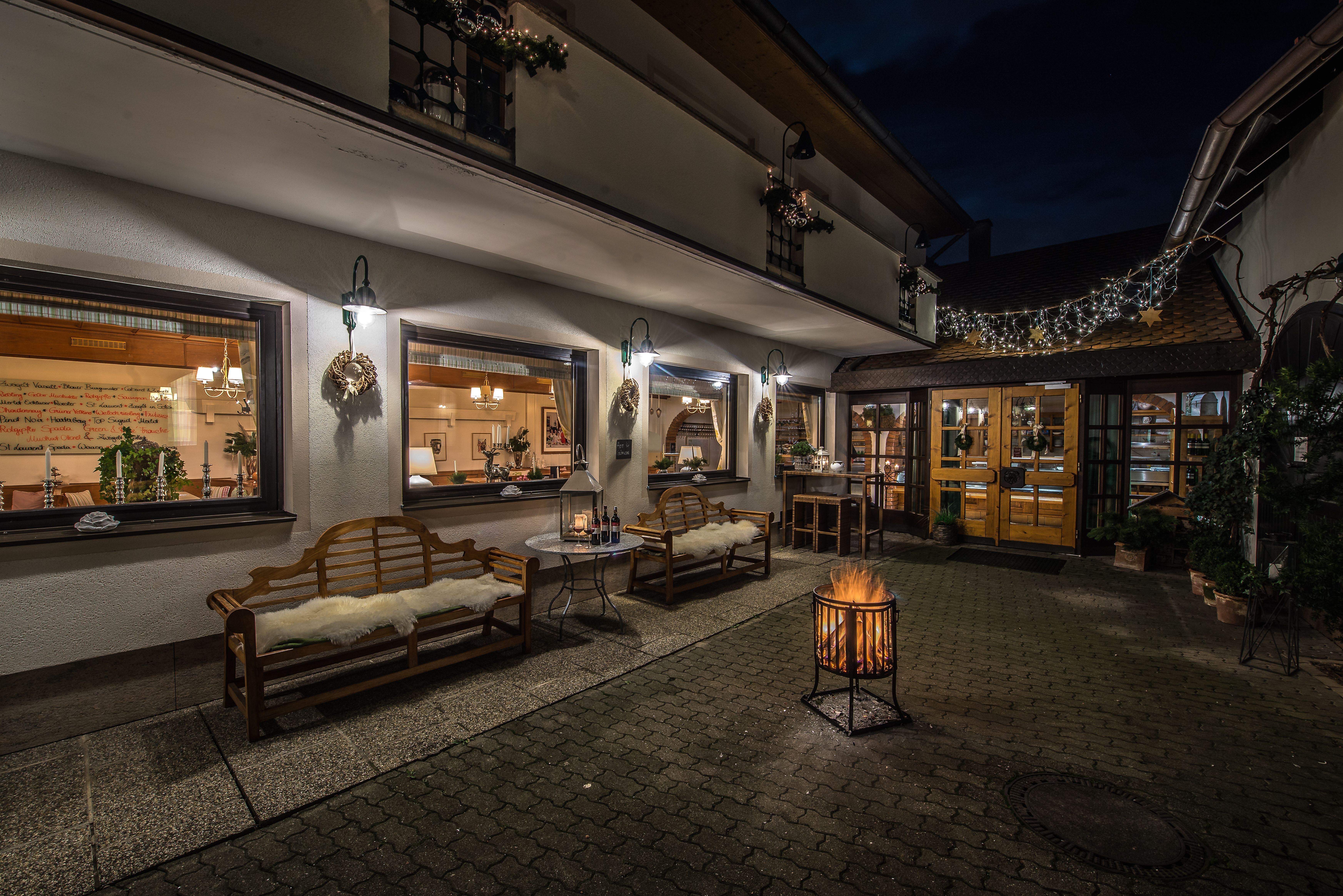 Gemütlicher Gartenbereich mit Holztisch und Stühlen, umgeben von Pflanzen und Weinreben.