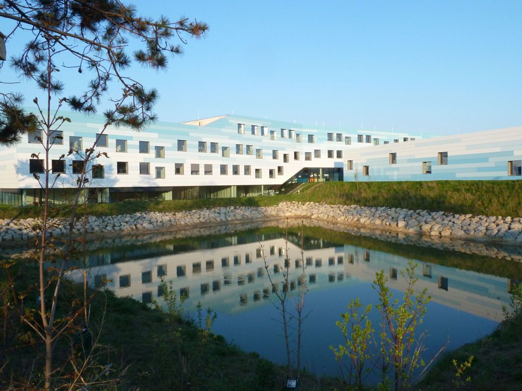 Modernes Gebäude mit blau-weißer Fassade und Teich im Vordergrund.
