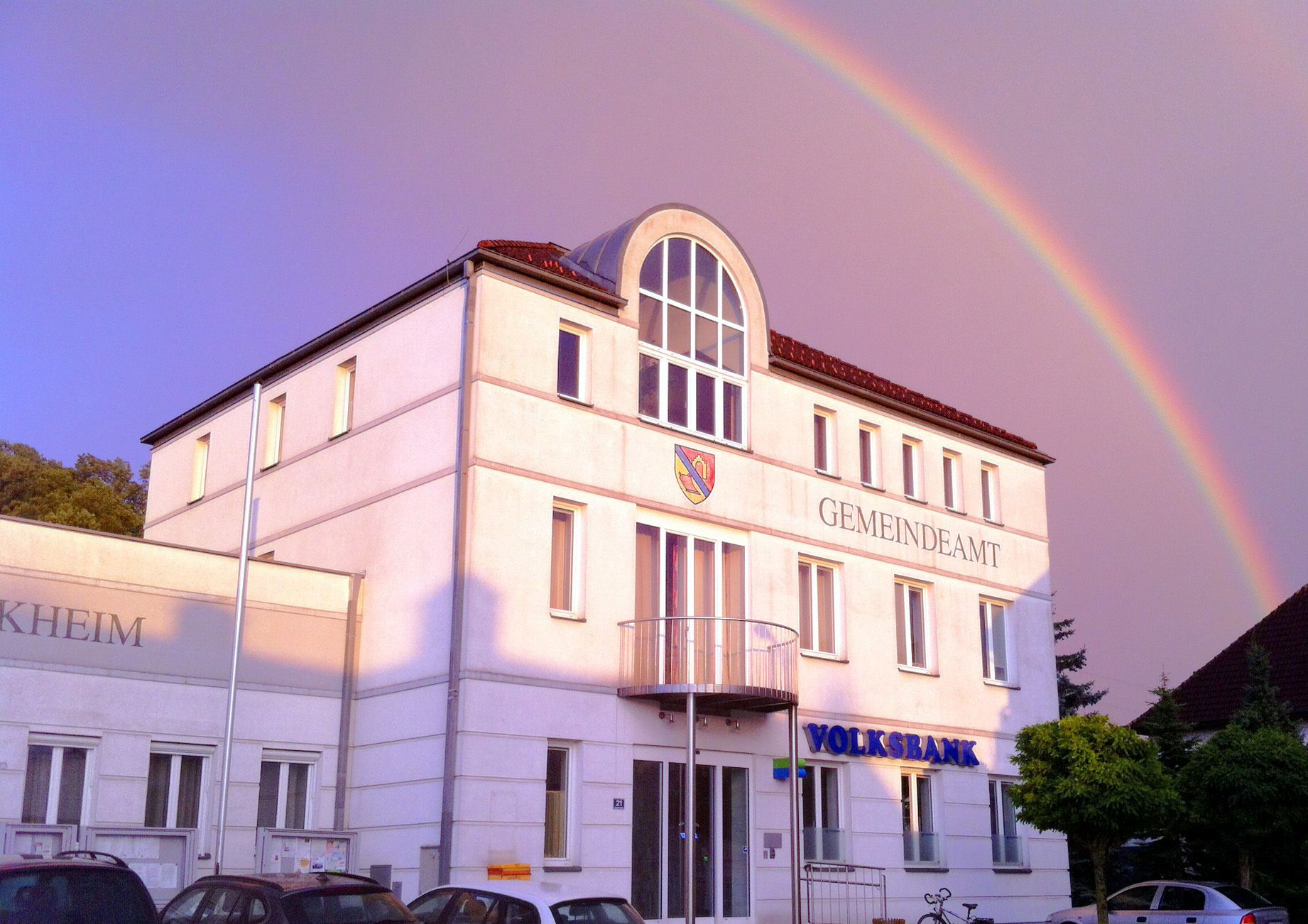 Gebäude des Gemeindeamts Ernsthofen mit Regenbogen im Hintergrund.