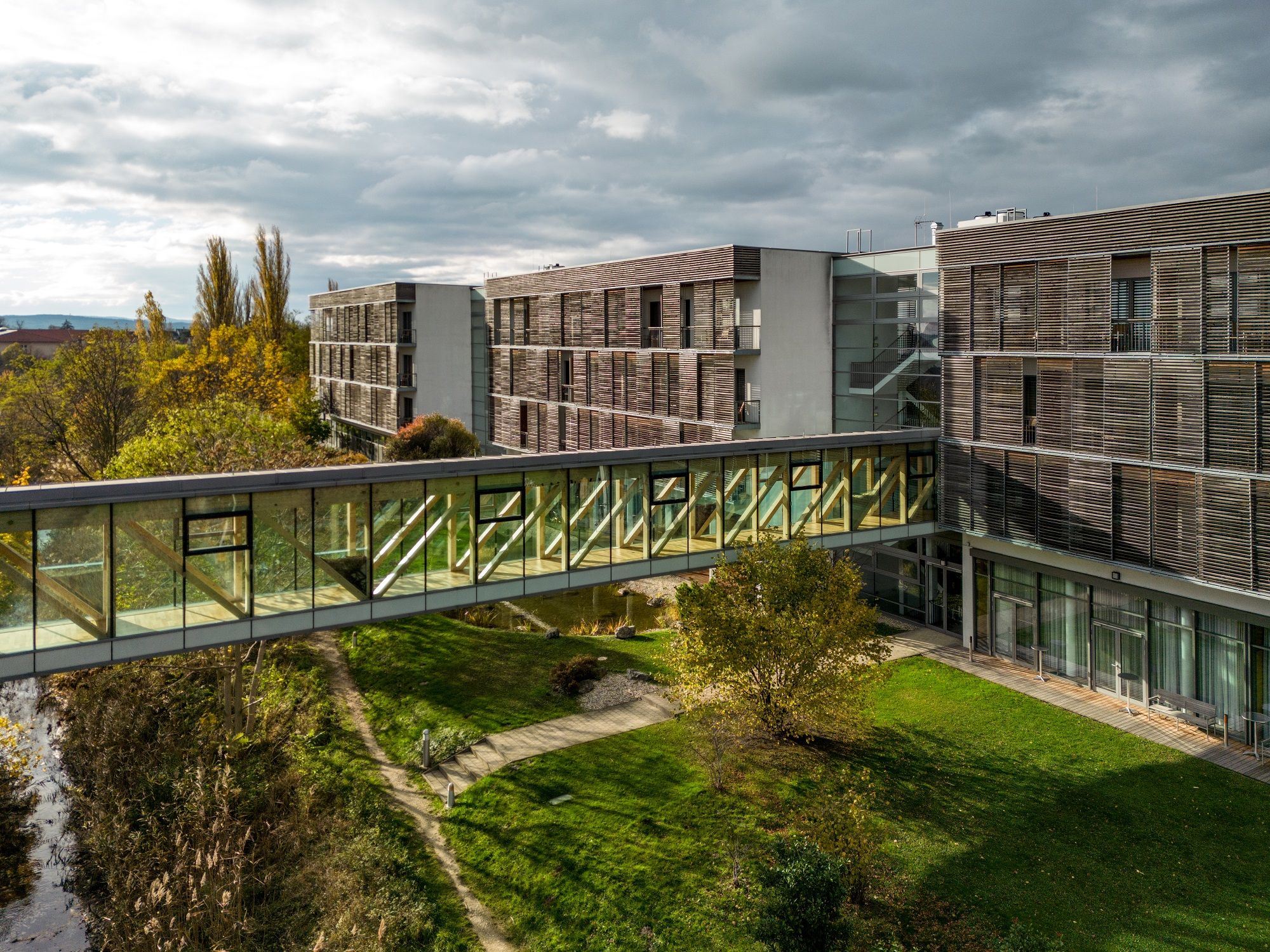 Moderne Hotelgebäude mit Glasbrücke und Garten.