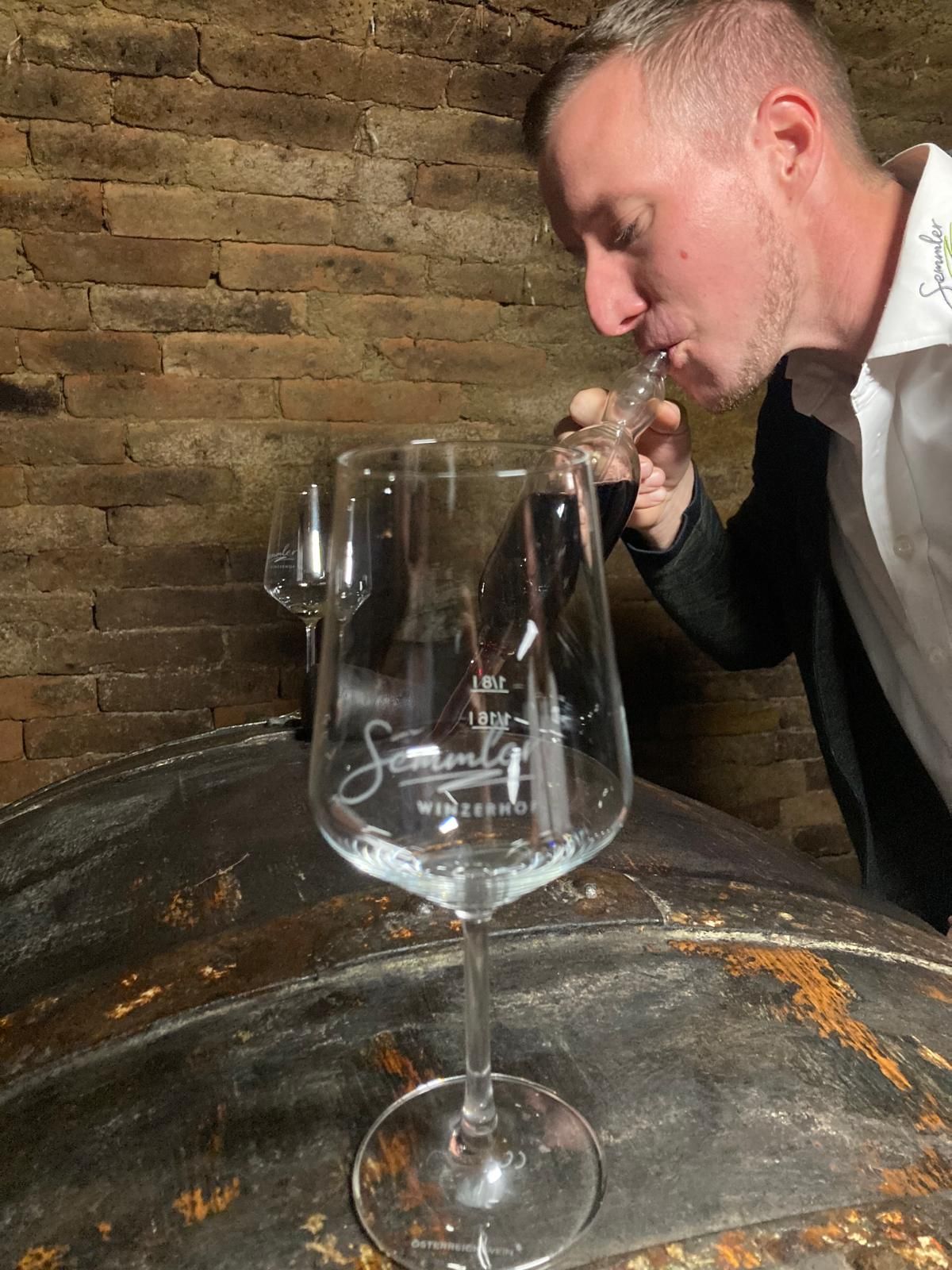 Ein Mann probiert Wein aus einer Pipette in einem Weinkeller.