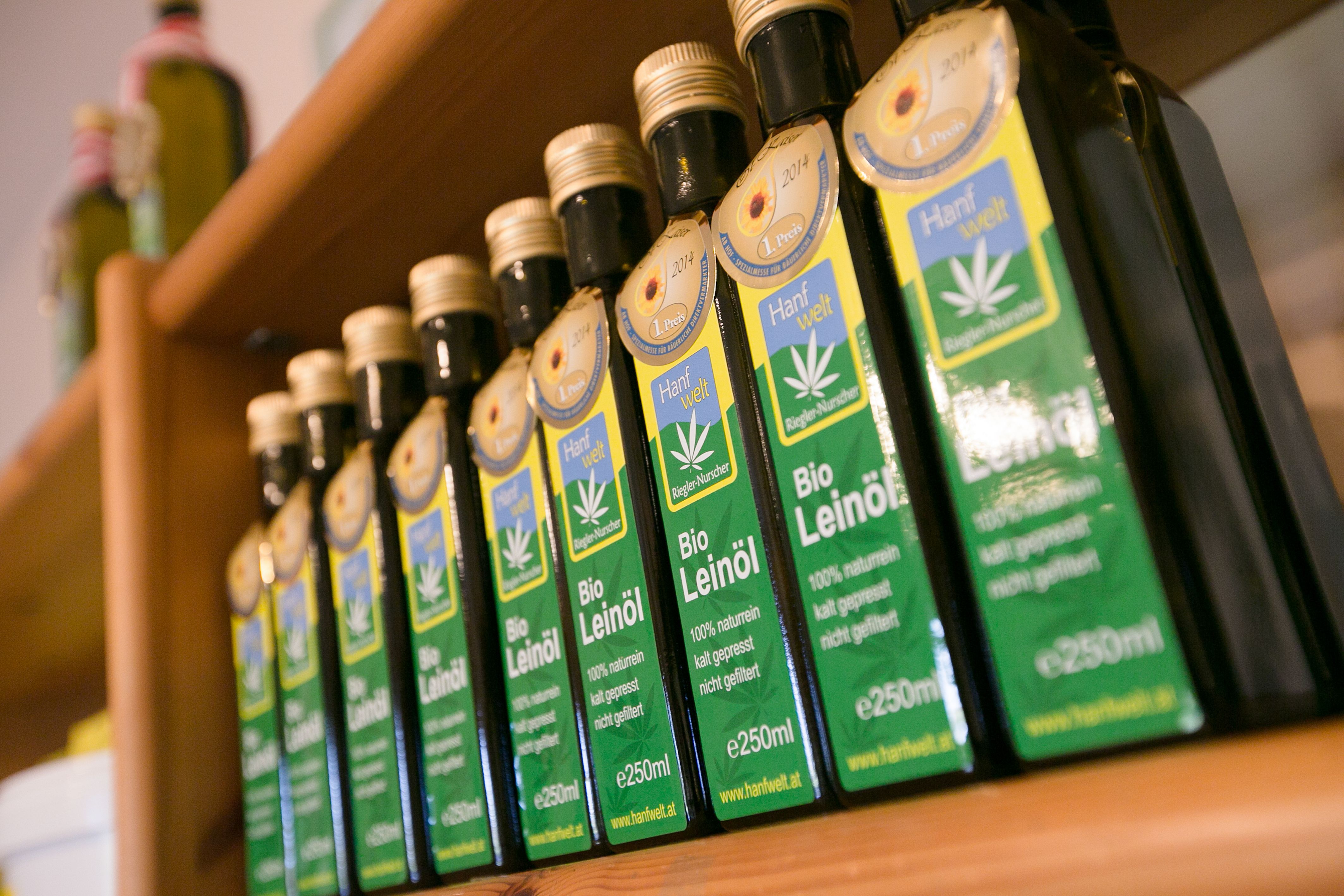Reihe von Bio-Leinölflaschen auf einem Holzregal.