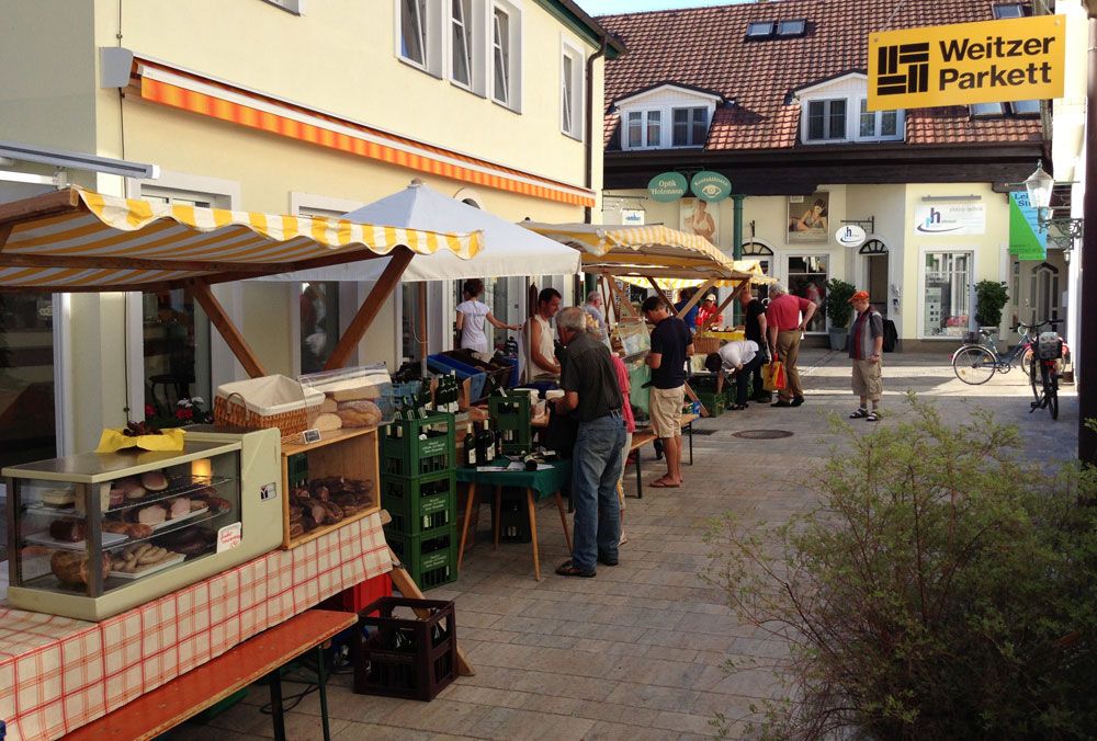 Bauernmarkt in einer Passage mit Ständen und Besuchern.