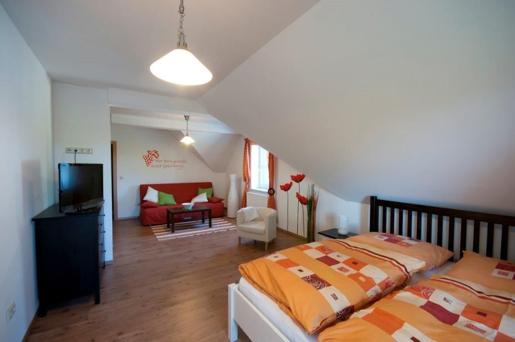 Gemütliches Gästezimmer mit Doppelbett, Sofa, Fernseher und dekorativen Elementen.