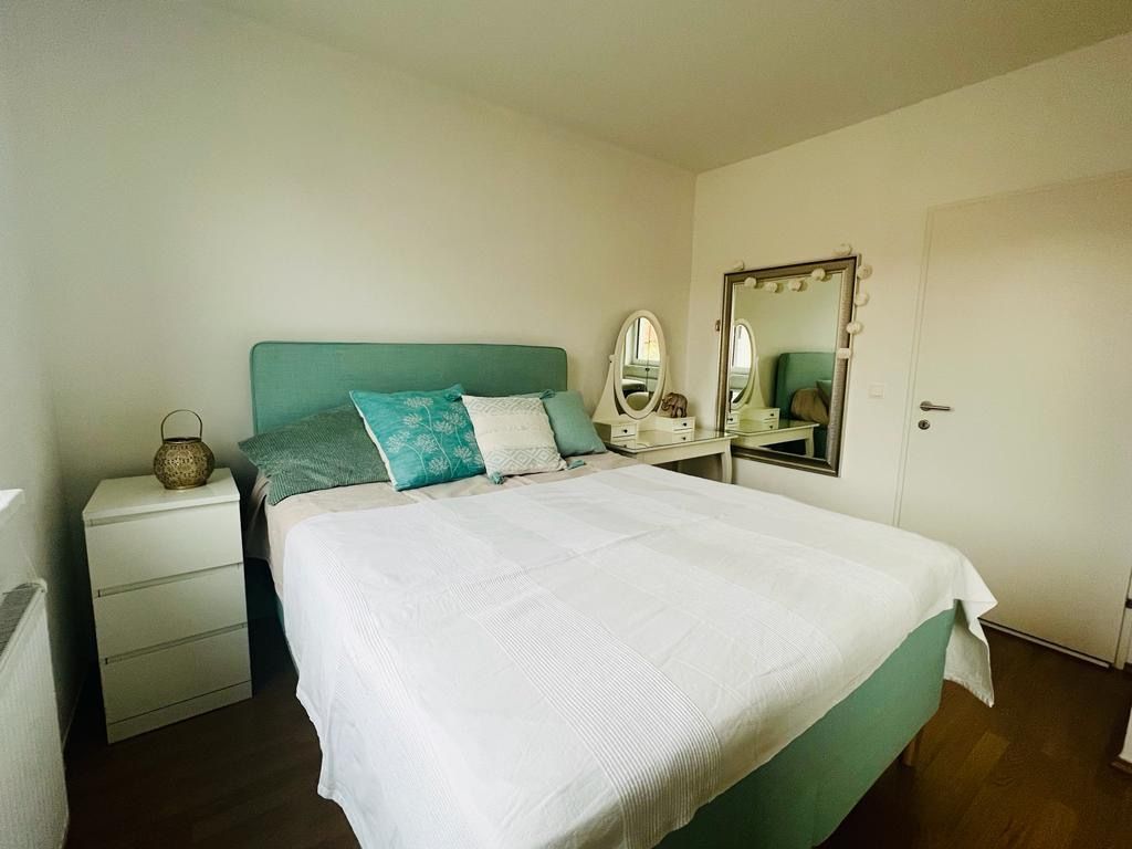 Schlafzimmer mit Doppelbett, Nachttisch und Schminktisch mit Spiegel.