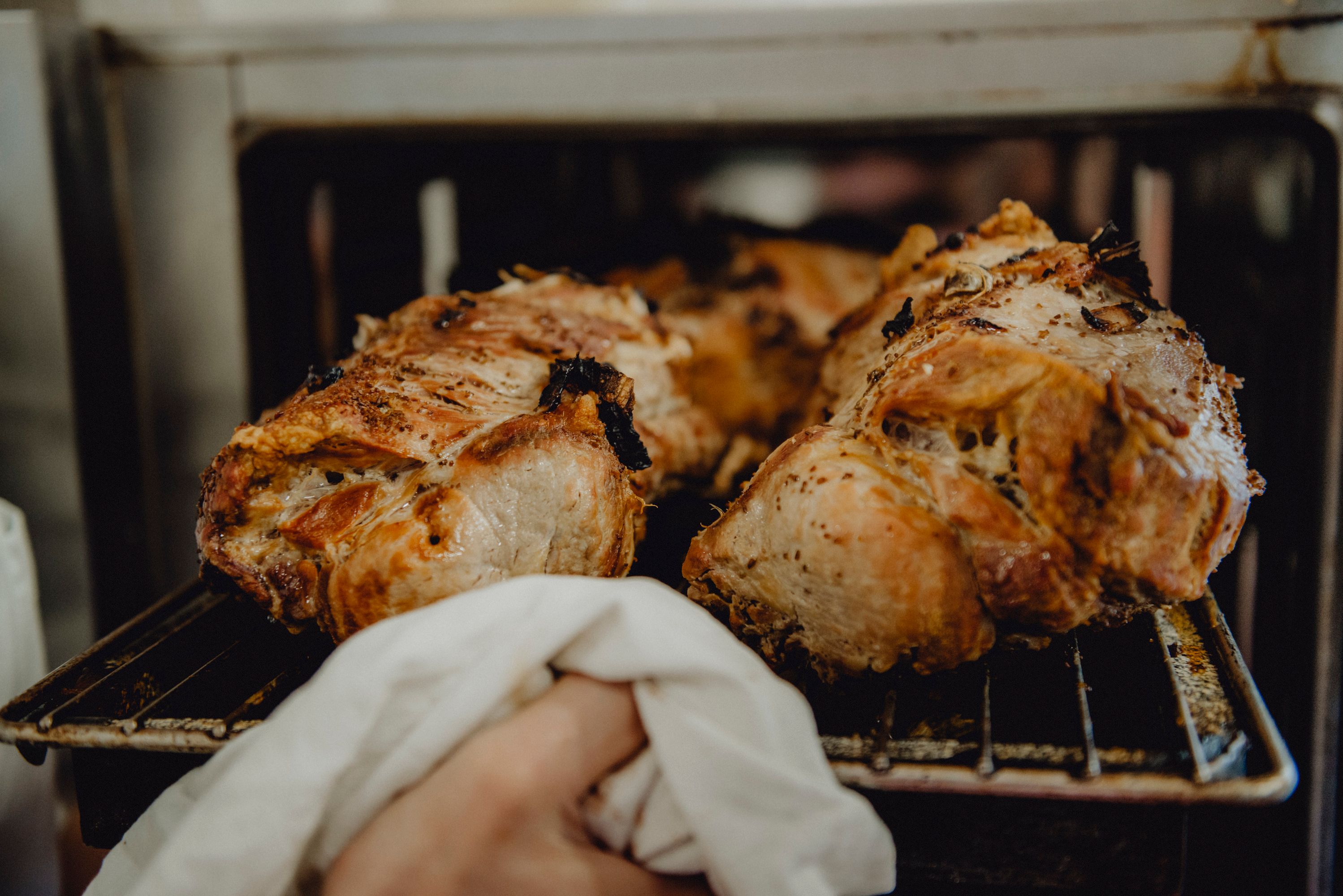 Frisch gebratenes Schweinefleisch wird aus dem Ofen genommen.