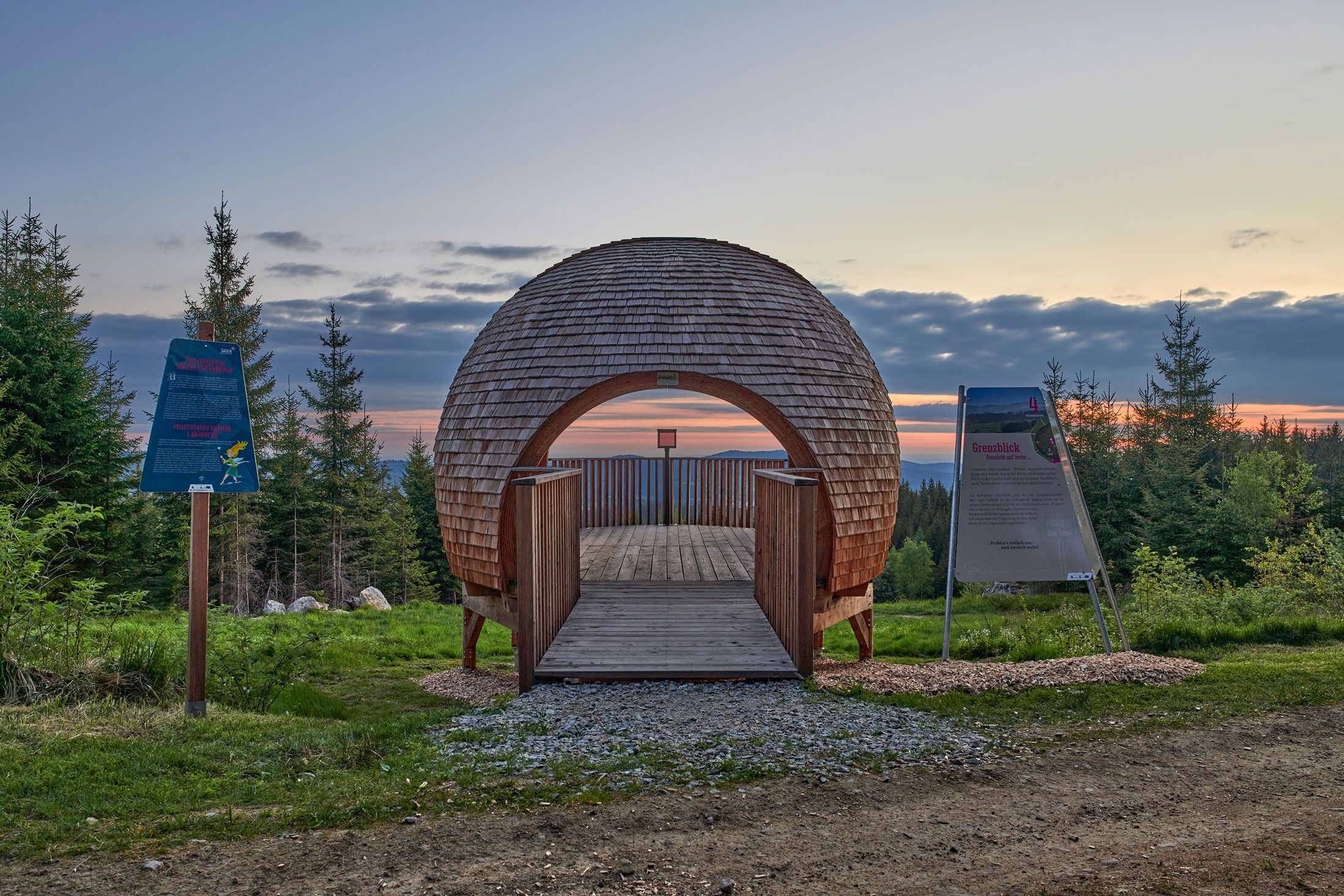 Aussichtsplattform Nebelstein Grenzblick in einer Waldlandschaft bei Sonnenuntergang.