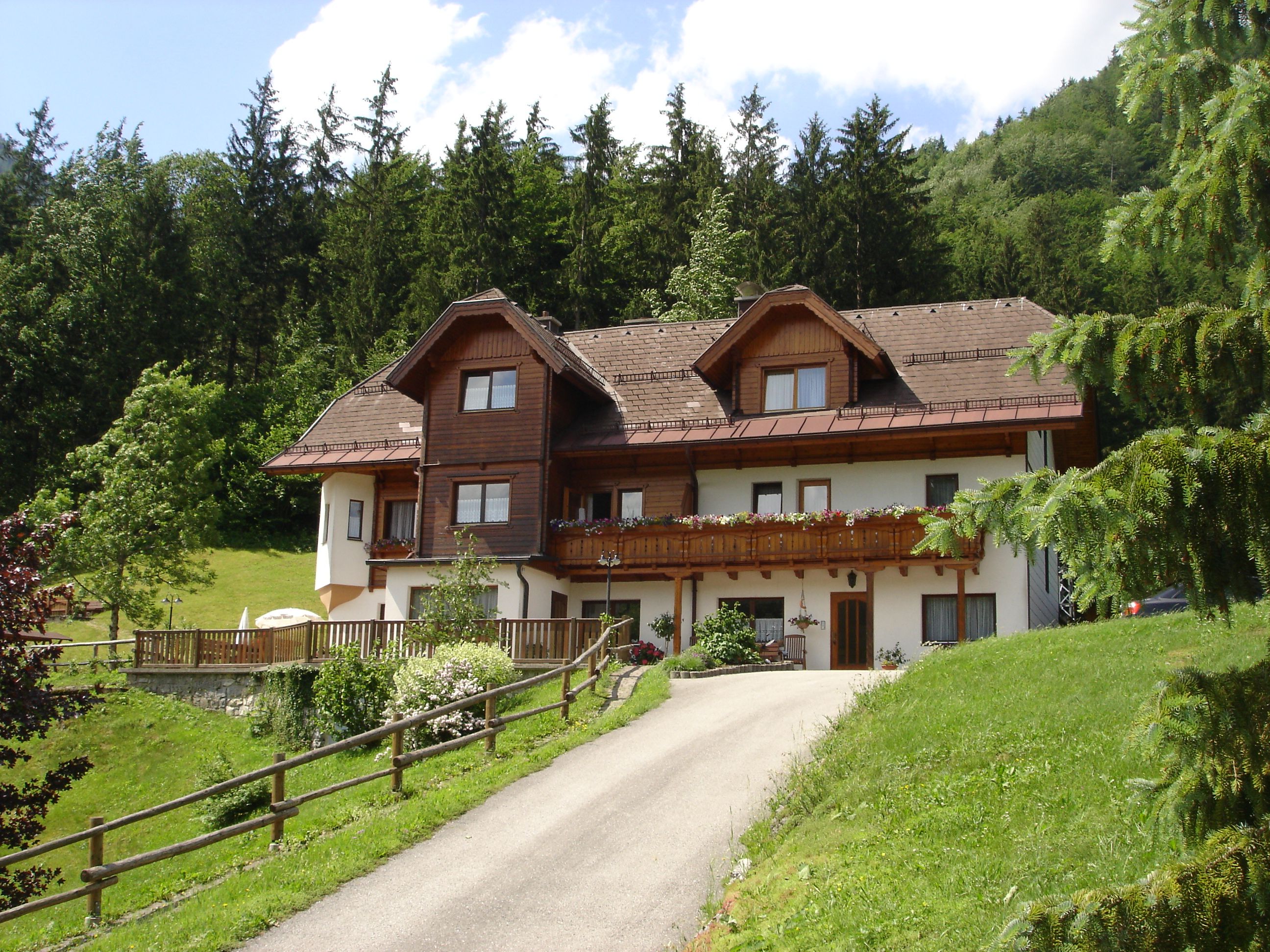 Ein traditionelles Haus mit Holzverkleidung in einer grünen, bewaldeten Umgebung.