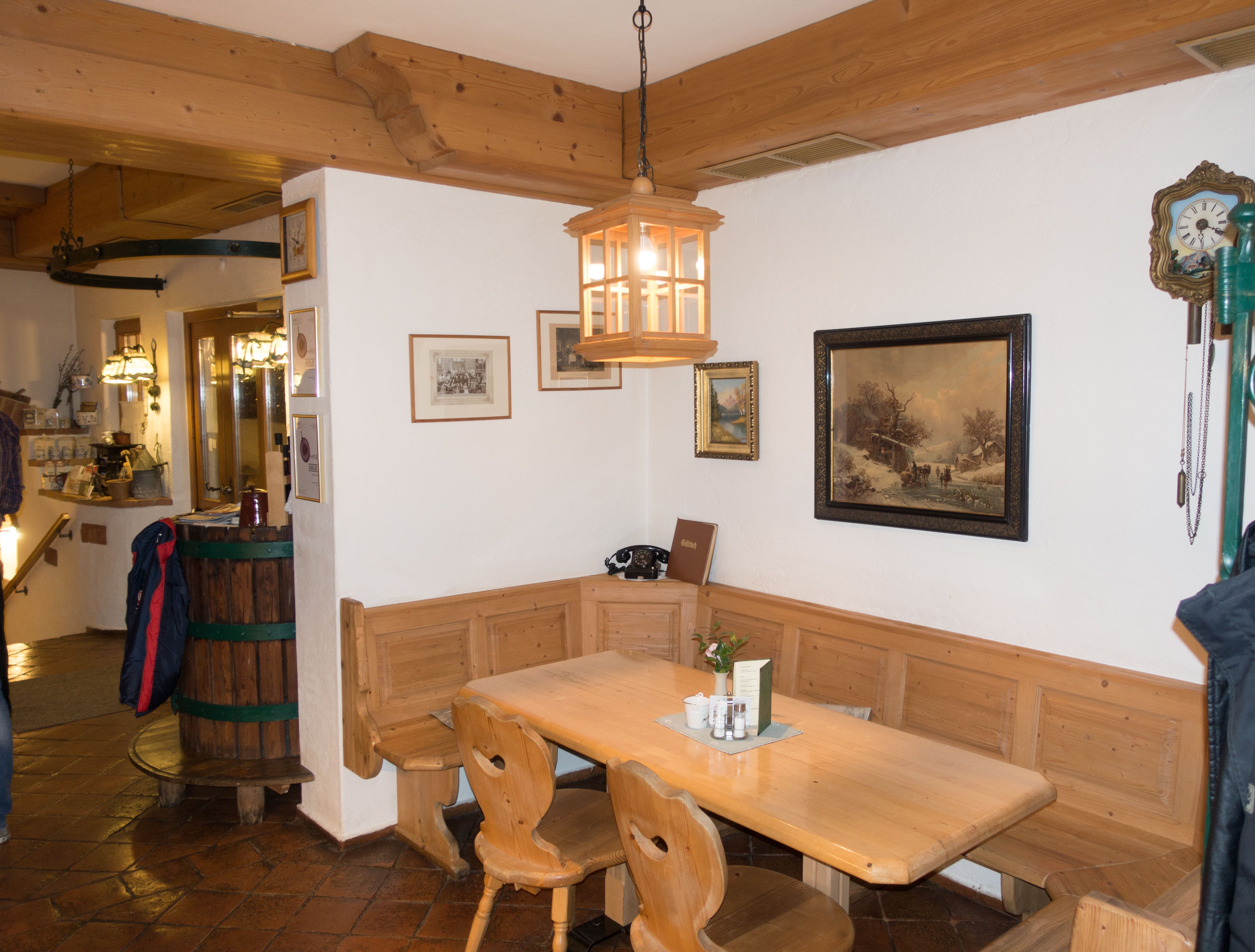 Gemütliche Holzecke in einem traditionellen Gasthaus mit Tisch, Stühlen und Wanddekorationen.