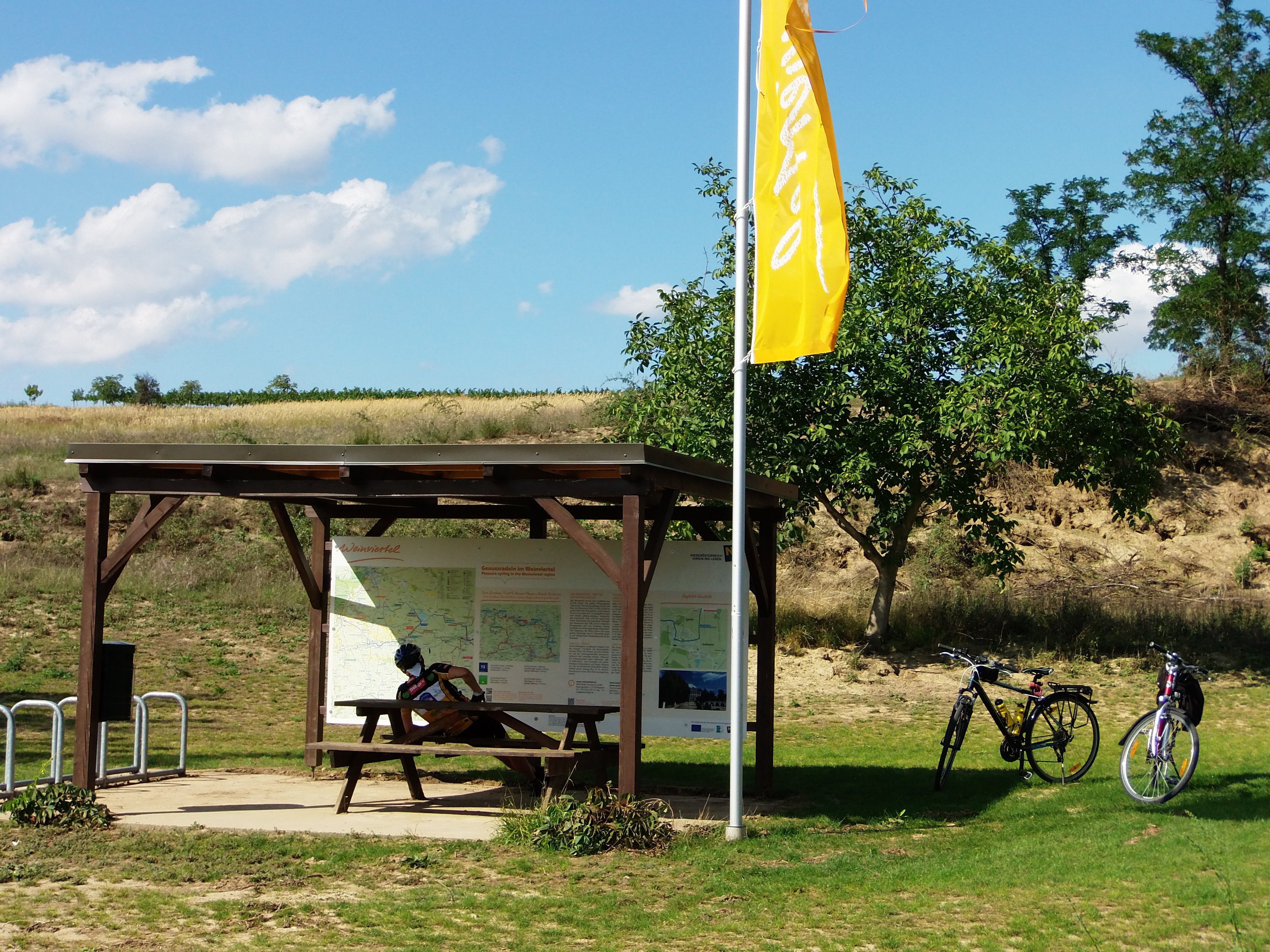 Radlerrastplatz mit Holztisch, zwei Fahrrädern und Infotafel im Weinviertel.