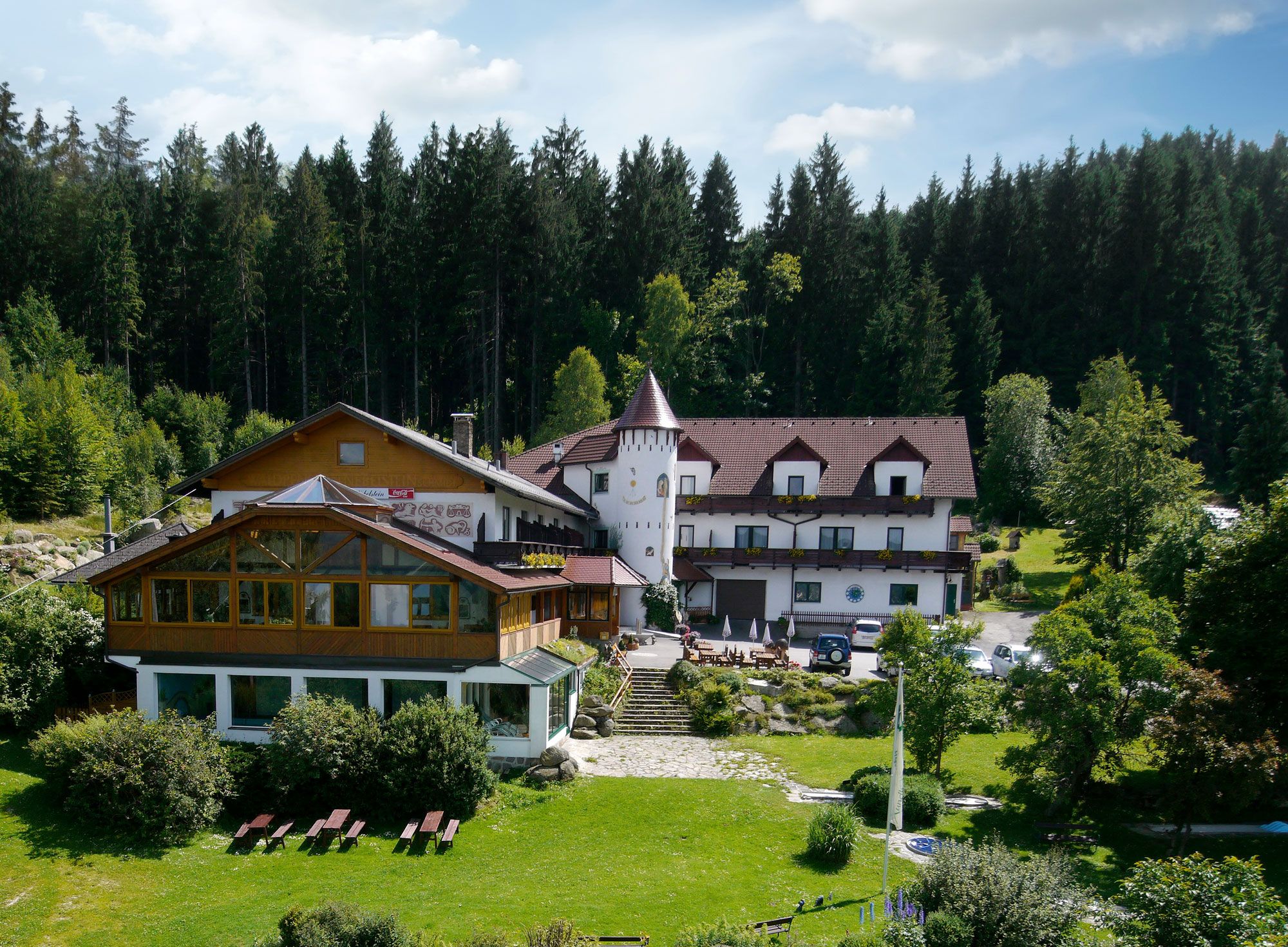 Märchenhotel Waldpension Nebelstein umgeben von Wald und Wiese.