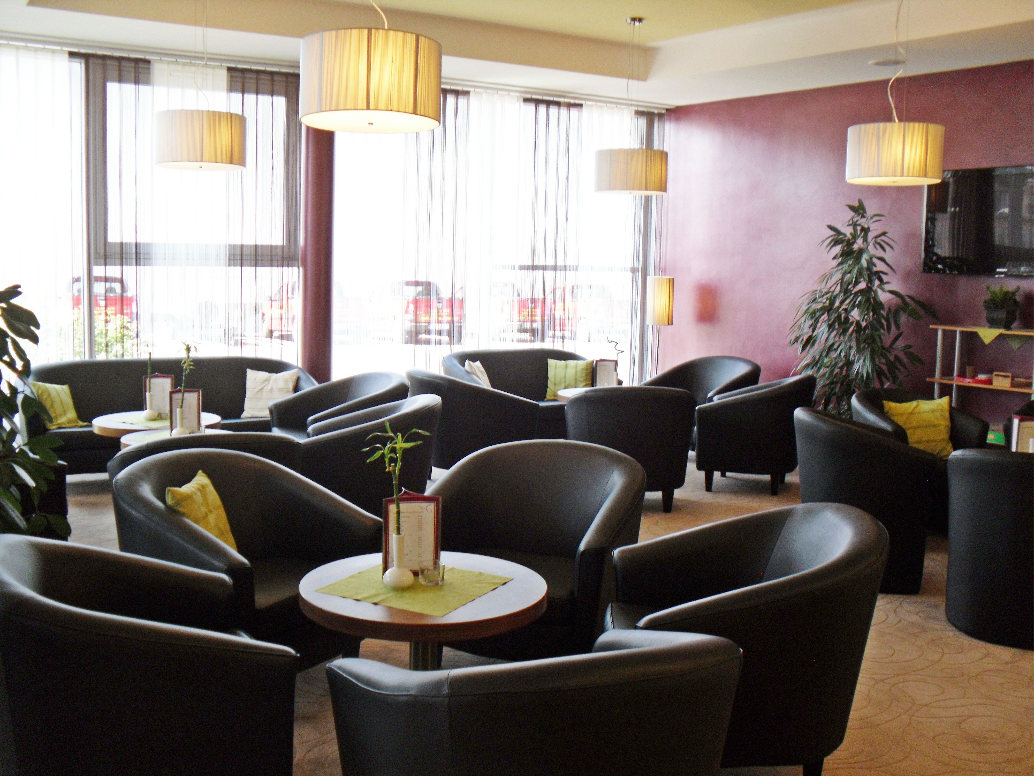 Moderne Lounge mit schwarzen Sesseln, runden Tischen und großen Fenstern.