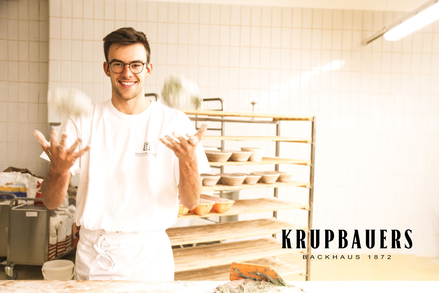 Ein Bäcker jongliert mit Teigbällen in einer Backstube.